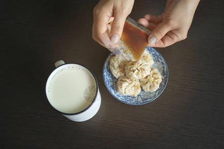 中式饭菜女人拿着家常酱油配中式点心舒麦和豆浆背景