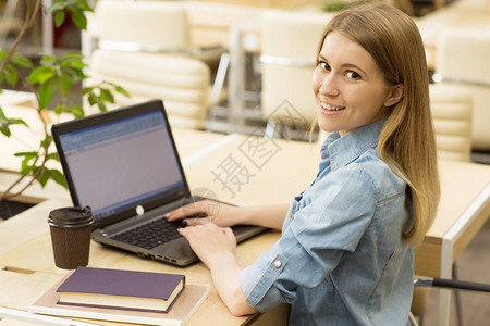 漂亮的年轻女子在她的笔记本电脑上浏览互联网图片