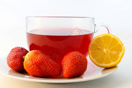 玻璃杯热芳香红茶与草莓和柠檬在白色背景图片