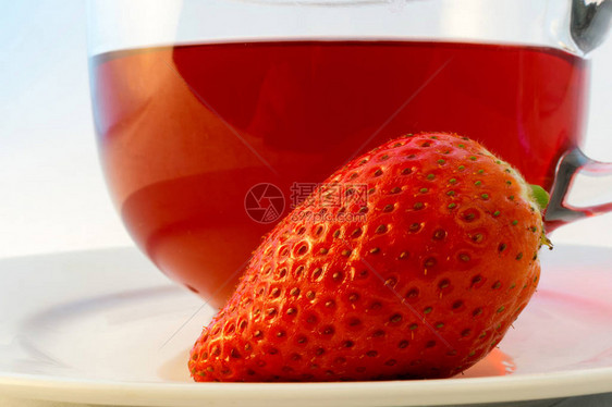 玻璃杯热芳香红茶与草莓在白色背景图片
