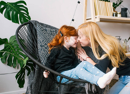母亲坐在家庭内部的扶手椅上亲吻红发小女儿家庭幸福图片
