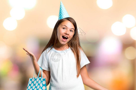 一个生日派对上的小姑娘拿着礼物袋带着惊喜和震惊的面部表情在无重图片