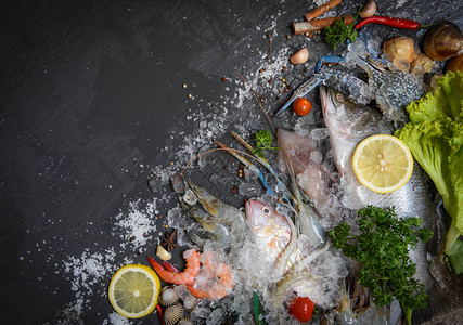 海鲜盘配贝类虾蟹壳蛤蜊鱿鱼章和海洋美食晚餐深色背景中带香草和香料柠檬图片