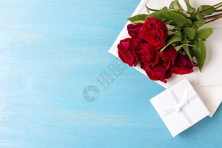 红玫瑰包白礼盒蓝木背景复制空间情人节假日的浪图片