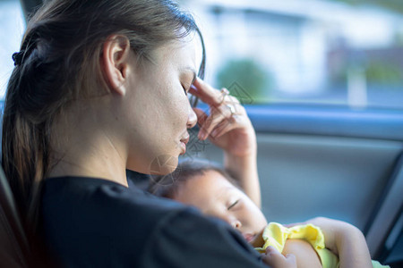 紧张的母亲在车里等待时抱着婴儿手抱着图片
