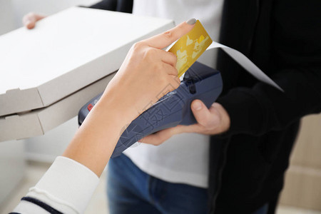 在室内使用银行终端支付信用卡的年轻妇女提供食品服务图片