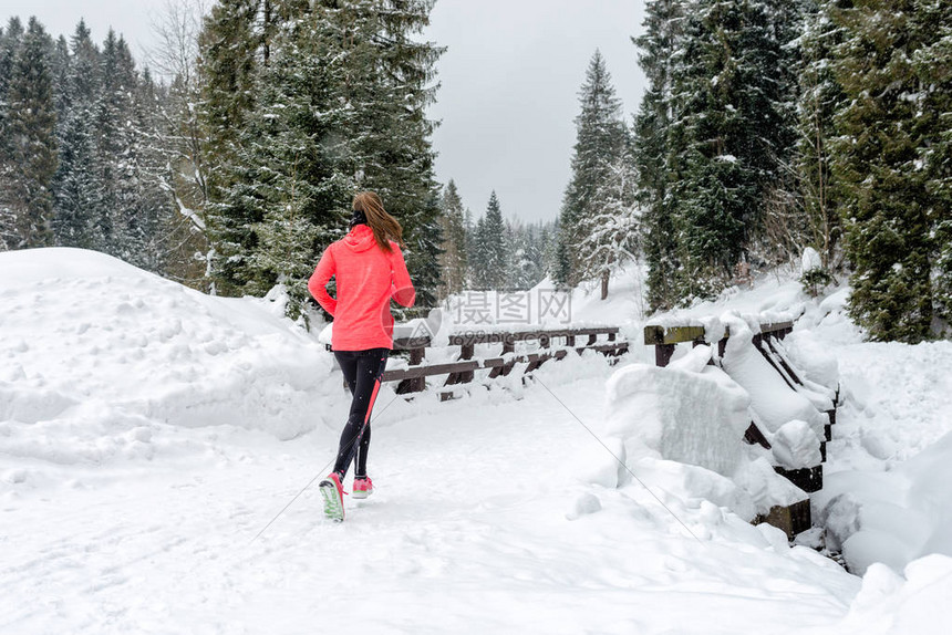 在雪天穿着保暖衣物手套在冬季山区的雪地上奔跑的年轻女子运动健身的灵感和动力快乐的少女子越野跑在户外慢图片