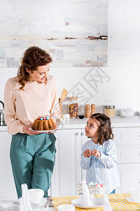 小孩带篮子妈带复活节蛋糕在厨房里图片