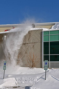 吹雪机操作员从建筑物中送出一阵雪图片