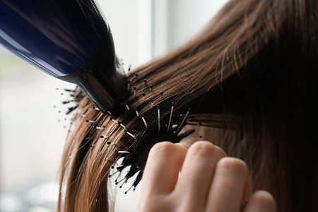发光机吹起干燥剂在美发店为年轻女子梳背景图片