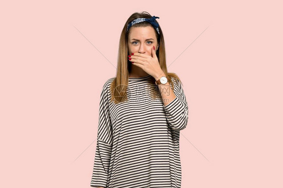 戴头巾的年轻女人用手亲张嘴说一些与孤立的粉红背景图片