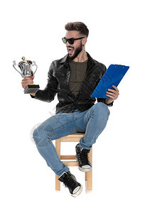 穿着黑色夹克和蓝色牛仔裤的男人坐在椅子上图片
