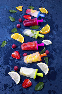 深蓝色背景中带有草莓樱桃柠檬橙子柠檬和薄荷香气和新鲜水果的多彩图片