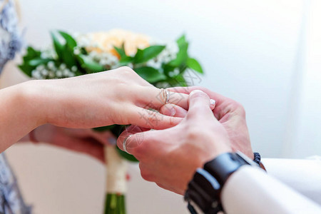 新娘和新郎的婚姻手与结婚戒指新郎手把结婚戒指放在新娘手指上爱的宣言图片