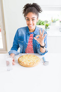 年轻非裔美国女人吃自制奶酪比萨饼用手指做好标记图片