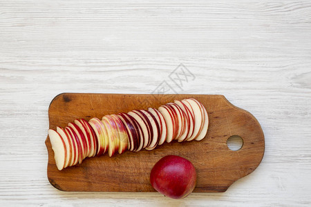 白色木制背景上的仿古木板上的新鲜红苹果片图片
