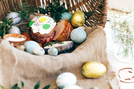 时尚的复活节彩蛋复活节面包蛋糕火腿甜菜香肠黄油柳条篮中的绿色树枝图片