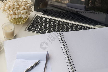 笔记本和笔点蜡烛放在一张看起来轻松的白桌子上图片