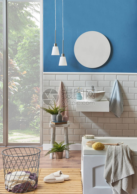 现代浴室与水槽细节与蓝色墙壁和陶瓷风格房间里的装饰镜子和台灯以及铺有木地板的白色浴缸拖鞋图片