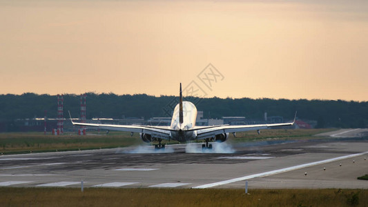 商业喷气式飞机在清晨降落到机场时接近跑道的后视线图片