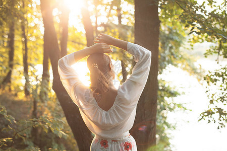 美丽的年轻女子站在阳光下站在森图片
