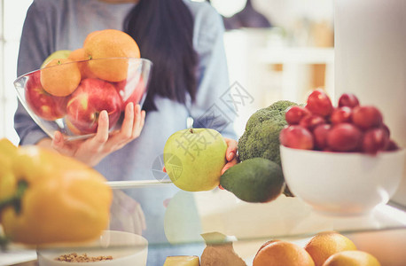微笑的女人从冰箱里取出新鲜水果健康的食物概念图片