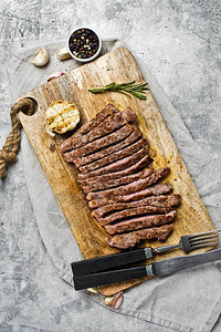木制切削板上的切片牛肉侧牛排灰色背景顶视图图片