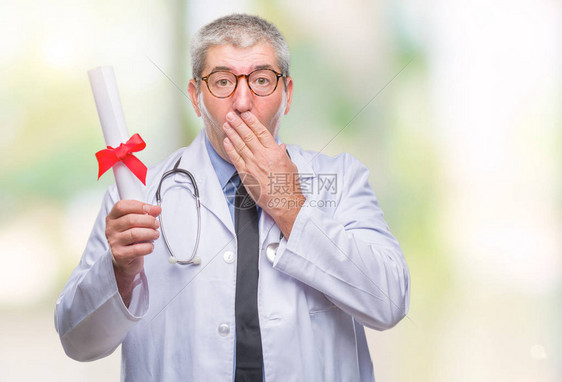 英俊的高级医生拿着学位论文在孤立的背景上用手捂住嘴图片