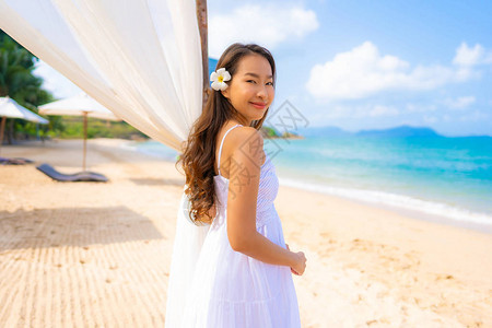 肖像美丽的亚洲年轻女子在沙滩海和洋上快乐微笑休闲图片