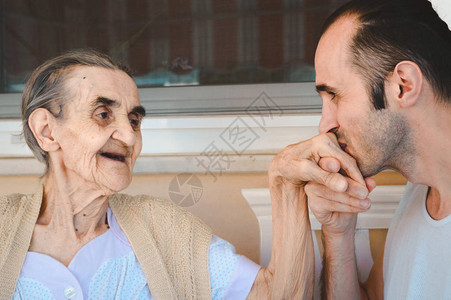 年轻男人亲吻他祖母的手表达他的爱图片