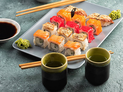 灰色盘子里的寿司卷和生鱼片图片