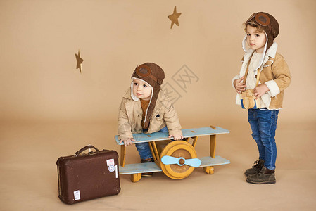 两兄弟用玩具飞机和米色背景的手提箱玩弄两个兄弟梦想图片