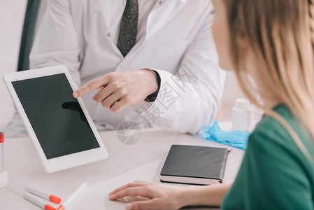 身穿白大衣的医生用手指着数字平板电脑的裁剪视图图片
