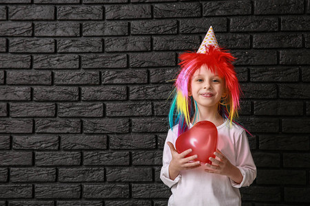 穿着明亮假发和深底气球的有趣的小女孩图片