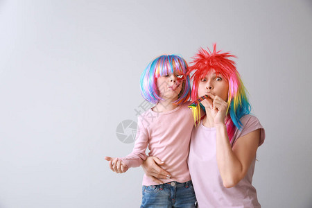 可笑的小女孩和她妈穿着光背景明亮的假发图片