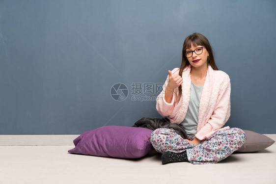 穿着睡衣的女人在地板上用拇指抬起来因图片