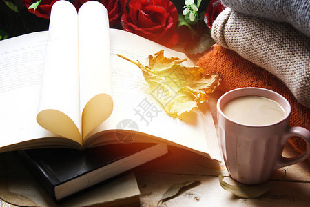 你好秋天卡秋天的静物一杯咖啡五颜六色的毛衣和枫叶红玫瑰花朵和木制背景纸质书的心形舒背景图片