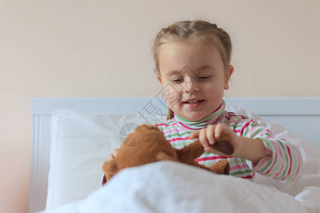 床上的小女孩抱着泰迪熊图片