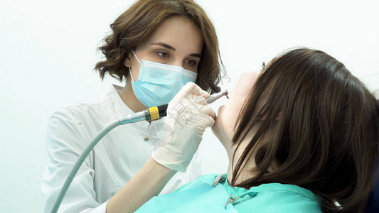 女牙医美白病人的牙齿媒体专业女牙医在使用新的无菌口腔科设备美白之前清图片