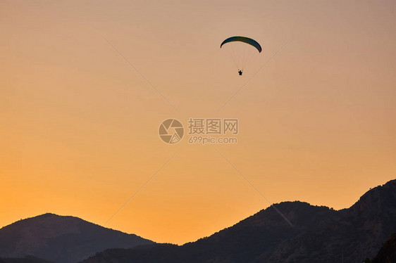 滑翔伞剪影以美丽温暖的日落色彩飞过迷雾笼罩的山谷充满自由的运动活跃壁纸背景与空间图片