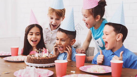 孩子生日派对男孩在蛋糕上吹图片
