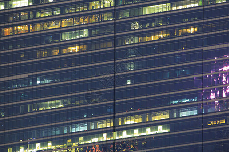 多层办公楼夜间与工人加班深夜在办公室照明和工作人员在玻璃钢和铝包覆的现代办图片