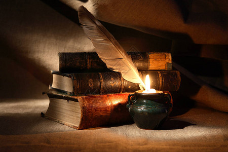 老式静物画在点燃蜡烛和书籍附近用鹅毛笔背景图片