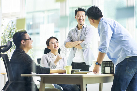 一组四位快乐的年轻亚洲人公司员工团队会议在办公室讨论业务背景图片