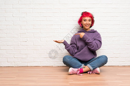 穿着粉色头发坐在地板上的年轻女人图片