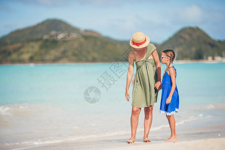 年轻美丽的母亲和可爱的小女儿在海滩上散步图片