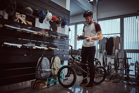 青少年BMX骑手站在自行车旁在商店里图片