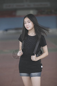 亚洲少年身穿黑色t恤背着包站在户外的肖像图片