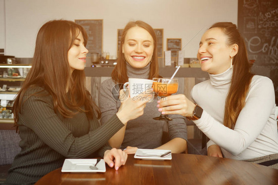 三个女朋友在咖啡馆见面喝饮料和聊天图片