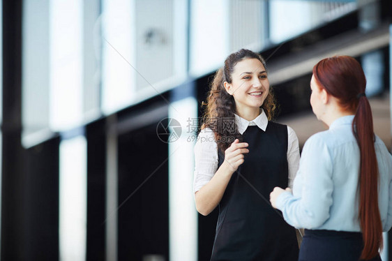 站在办公大厅复制空间上与同事交谈的年轻女商业女商图片